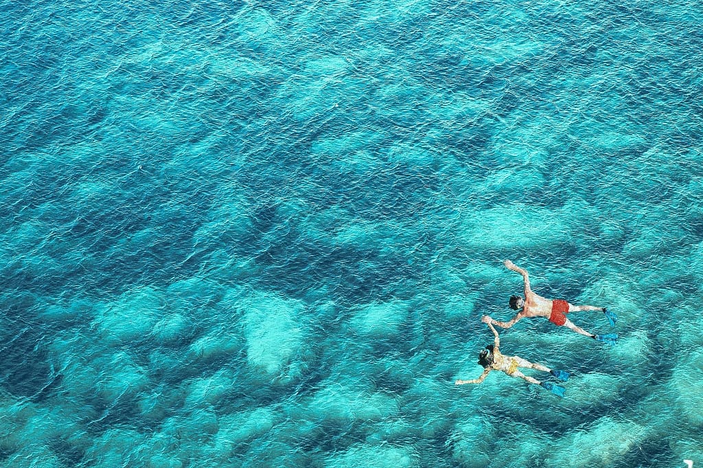 Above view of couple snorkeling in blue sea water. Summer vacation concept